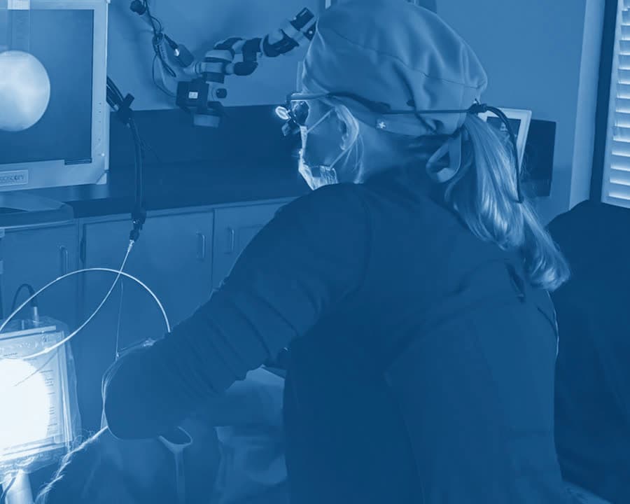 A Perio One clinician in magnifying loupes guiding the periodontal endoscope during treatment